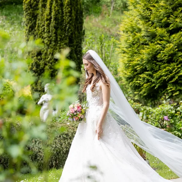 Braut im langen Hochzeitskleid im Garten von SchlossFUN Seeburg