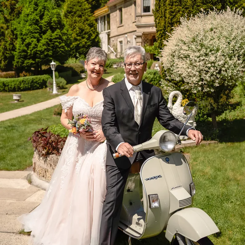 Brautpaar mit der Dolce Vita Vespa vor SchlossFUN Seeburg