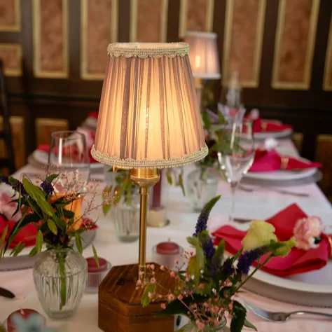 Elegante Tischdekoration mit Blumen, roten Servietten und Tischleuchte im SchlossFUN