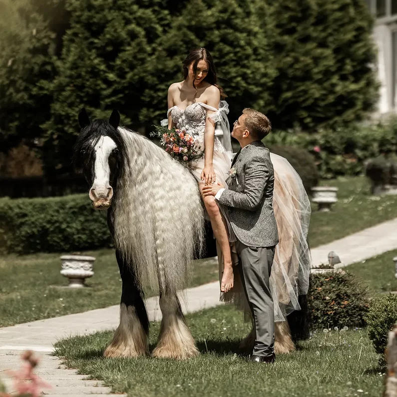 Braut auf dem Pferd mit Bräutigam im Schlossgarten von SchlossFUN Seeburg