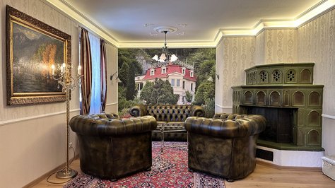 Gemütliches Wohnzimmer der Romantik-Suite im SchlossFUN in Seeburg bei Bad Urach mit historischem Kachelofen und stilvoller Einrichtung.