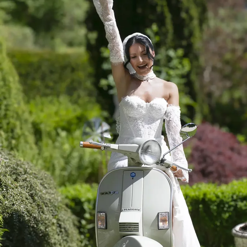Braut auf der Dolce Vita Vespa im Garten von SchlossFUN Seeburg
