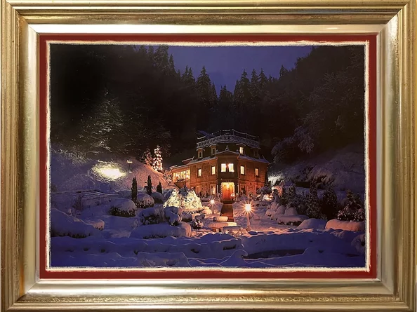 Winterliche Aufnahme des festlich beleuchteten Schlössle Seeburg mit verschneitem Garten und Waldkulisse bei Nacht.