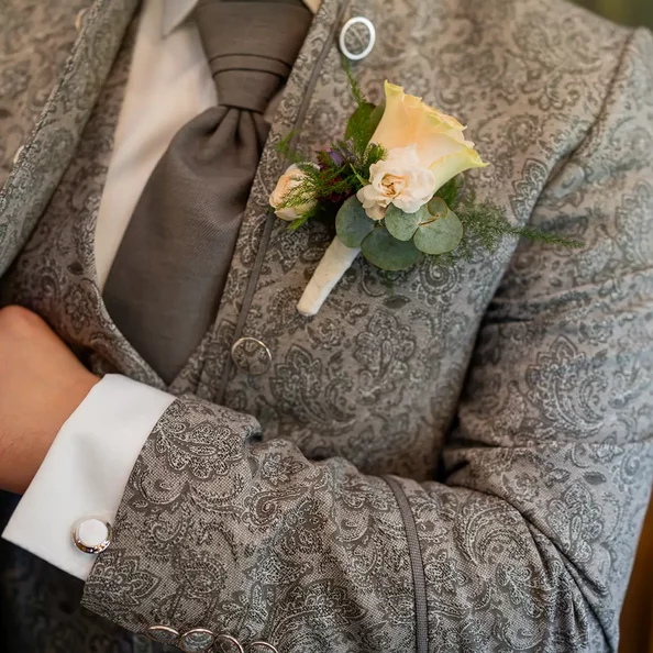 Detail eines Hochzeitsanzugs mit Krawatte und Blumenanstecker im SchlossFUN Seeburg