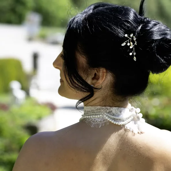 Braut mit eleganter Hochsteckfrisur und Haarschmuck im Garten von SchlossFUN Seeburg