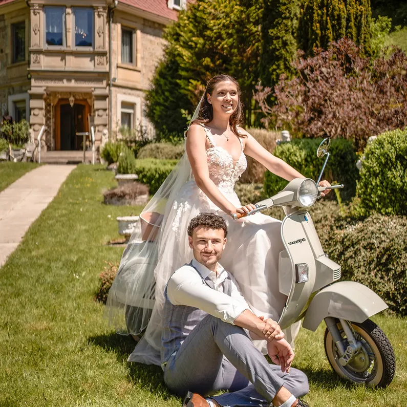 Brautpaar mit der Dolce Vita Vespa im Schlossgarten von SchlossFUN Seeburg