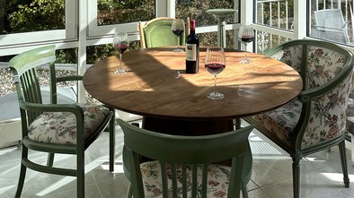Heller Wintergarten der Suite Nachtigall im Schlössle Seeburg mit rundem Holztisch, grünen Stühlen und Zugang zur Terrasse.